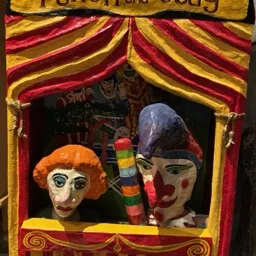 Un colorido castillo de Punch and Judy con Judy y un títere payaso actuando.