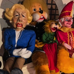 Picture of a Lion puppet and a Margaret Tacher ventriloguist puppet. 